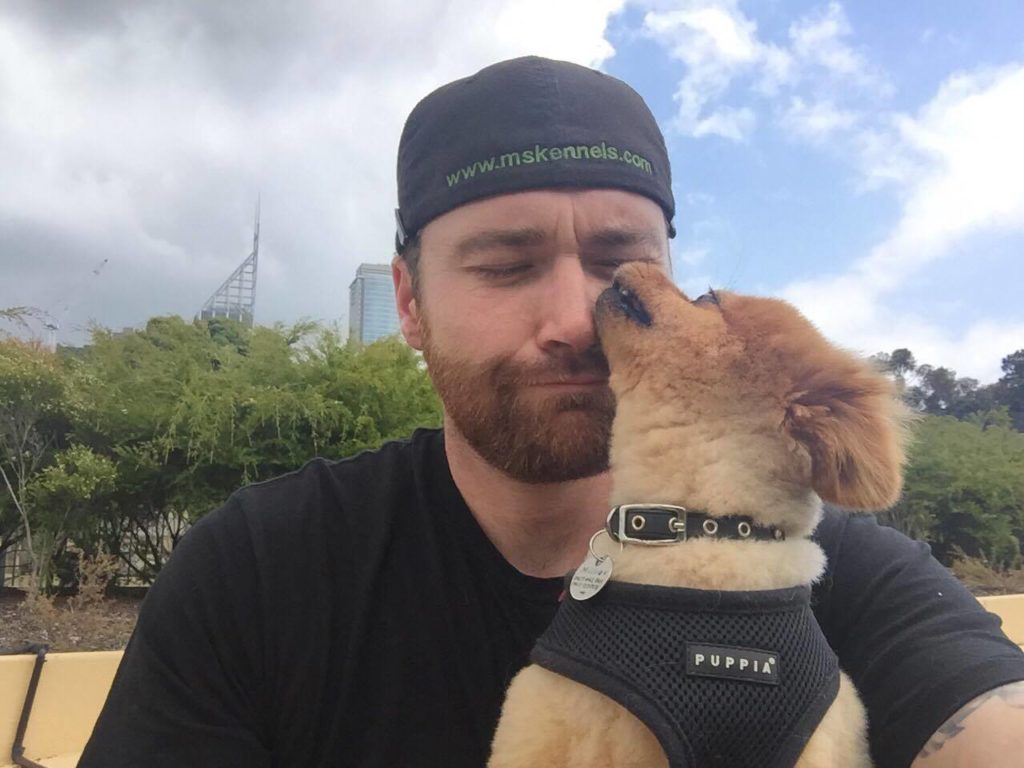 Pat Stuart with a puppy client licking his face